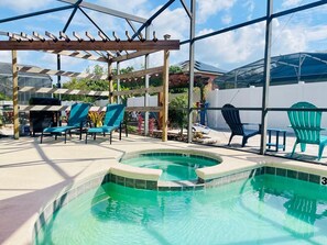 Un espace piscine agrémenté d’une pergola, de chaises longues et d’une structure fermée par des parois de verre.
