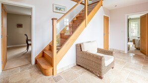 Un escalier avec des rampes en bois et une chaise en osier dotée d’un coussin.