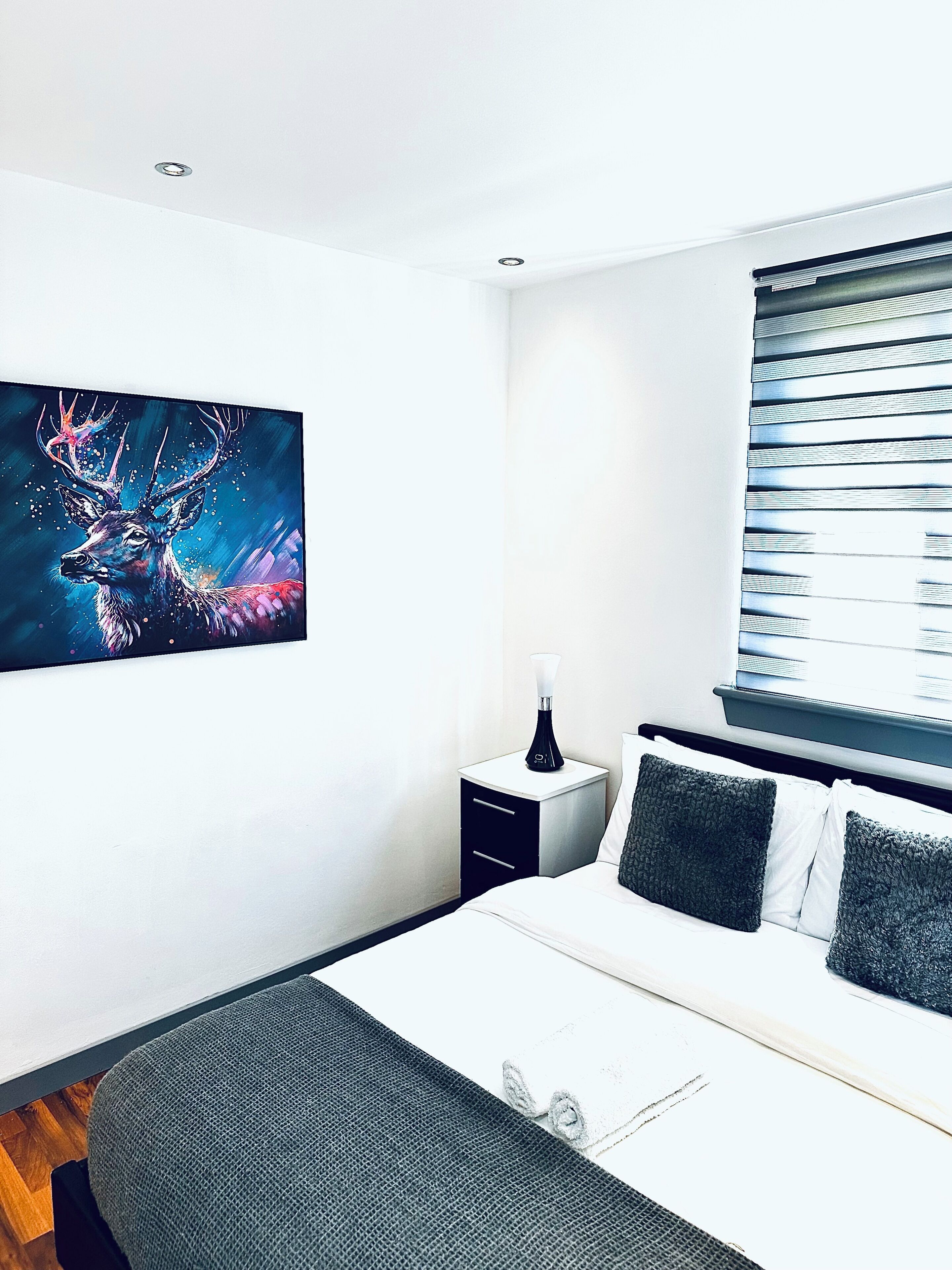 A modern bedroom with a bed, bedside table, and a large wall painting.
