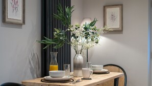 A dining table with a vase of flowers, a glass of orange juice, and a pitcher. - Pilgrim Cottage - Luxury Cottages (Chester)