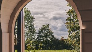 Un arco di ingresso conduce a un prato verde con una panchina di legno e una recinzione.
