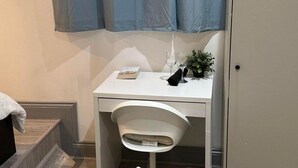 A small, white desk with a chair, a glass of water, a book, and a small plant. - Studio Sleeps 3 - Outdoor Space - Pet Friendly (London)