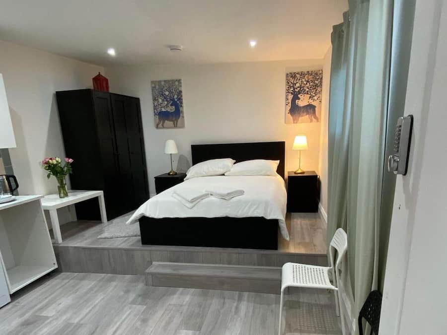 Una habitación de hotel moderna con una cama, mesitas de noche, un escritorio, una lavadora y obras de arte en las paredes.