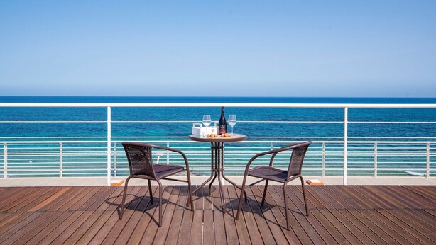 A deck with two wicker chairs and a round table, overlooking a clear blue sea. - Aquamarine apartment (Avola)
