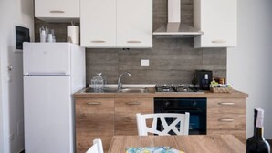 A modern kitchen with white cabinets, a wooden countertop, a gas stove, and a dishwasher. - Aquamarine apartment (Avola)