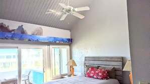 Quarto com cama, ventilador de teto, janela e vista para o exterior.