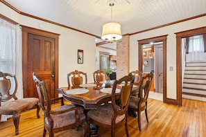 A dining room with a wooden table, chairs, and a hanging light fixture. - Spacious 4 BDRM w/Onsite Parking & A/C! (Rochester)