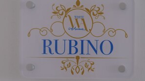 A sign with the text "WHITE RUBINO" and decorative elements. - Ruby Apartment (Avola)