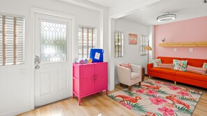 A living room with a pink cabinet, a white door, and a red sofa. - Flamingo 1BR Beach-side Villa in Siesta Key - Pool (Siesta Key)