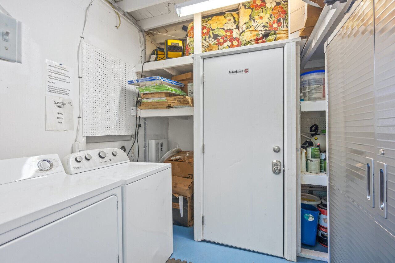 Een ruime wasruimte met een Whirlpool wasmachine, een kleine koelkast en planken met schoonmaakmiddelen.