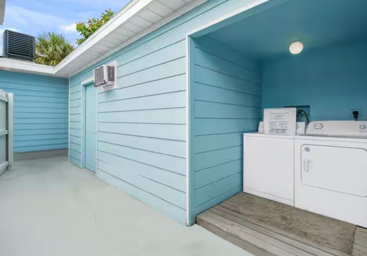 A laundry room with a blue exterior wall and a white washing machine.