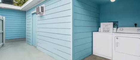 A laundry room with a blue exterior wall and a white washing machine.