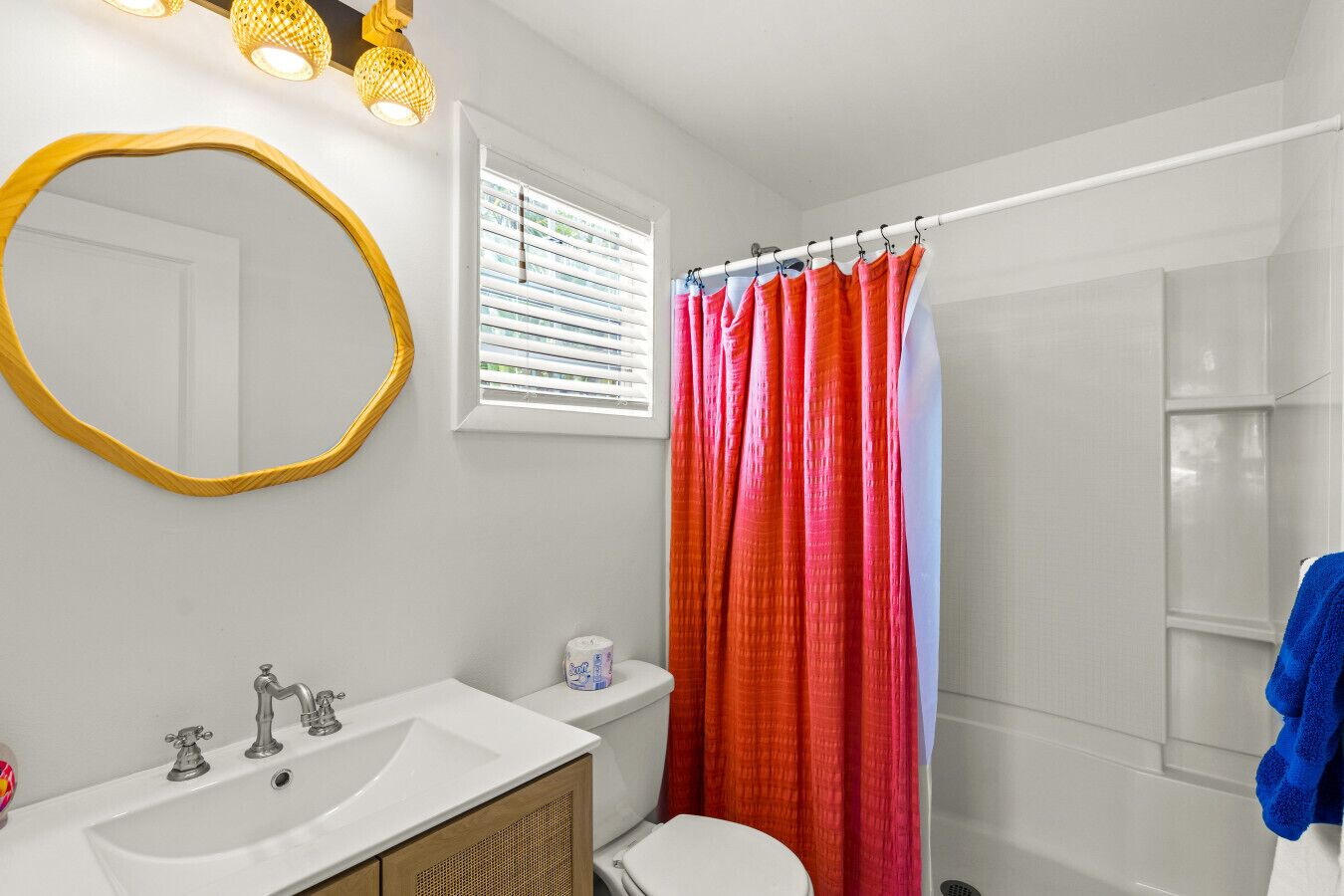 Une salle de bain avec un lavabo blanc, un miroir, des toilettes et un rideau de douche.