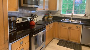 A modern kitchen with wooden cabinets, a stainless steel stove, a microwave, and a sink. - Macklyn Creek retreat (Brookings)