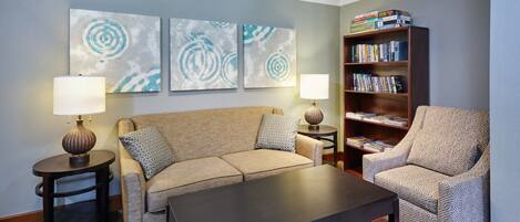 A living room with a sofa, armchair, coffee table, side tables, lamps, and a bookshelf.