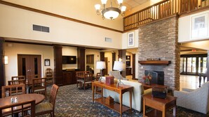 Un hall d’entrée spacieux avec une cheminée, des meubles en bois et un tapis à motifs.