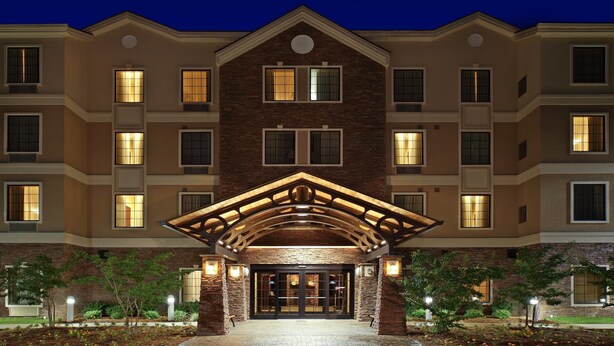 Un hôtel à plusieurs étages, doté d’une entrée imposante, avec une arche en bois et des fenêtres illuminées.