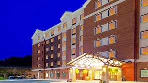 A multi-story hotel with a brick facade, a covered entrance, and a sign indicating Staybridge Suites. - 1 Bedroom | Shared Indoor Pool + Business Center (Stafford)