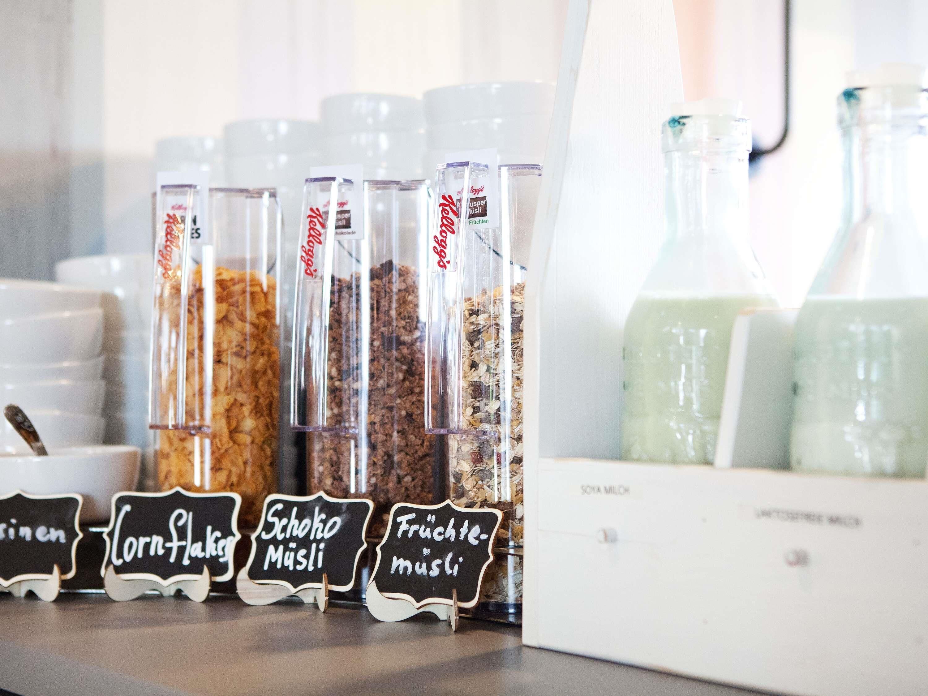 A selection of food items in transparent containers with labels, and a white box with a label that reads 'Soya Milch'.