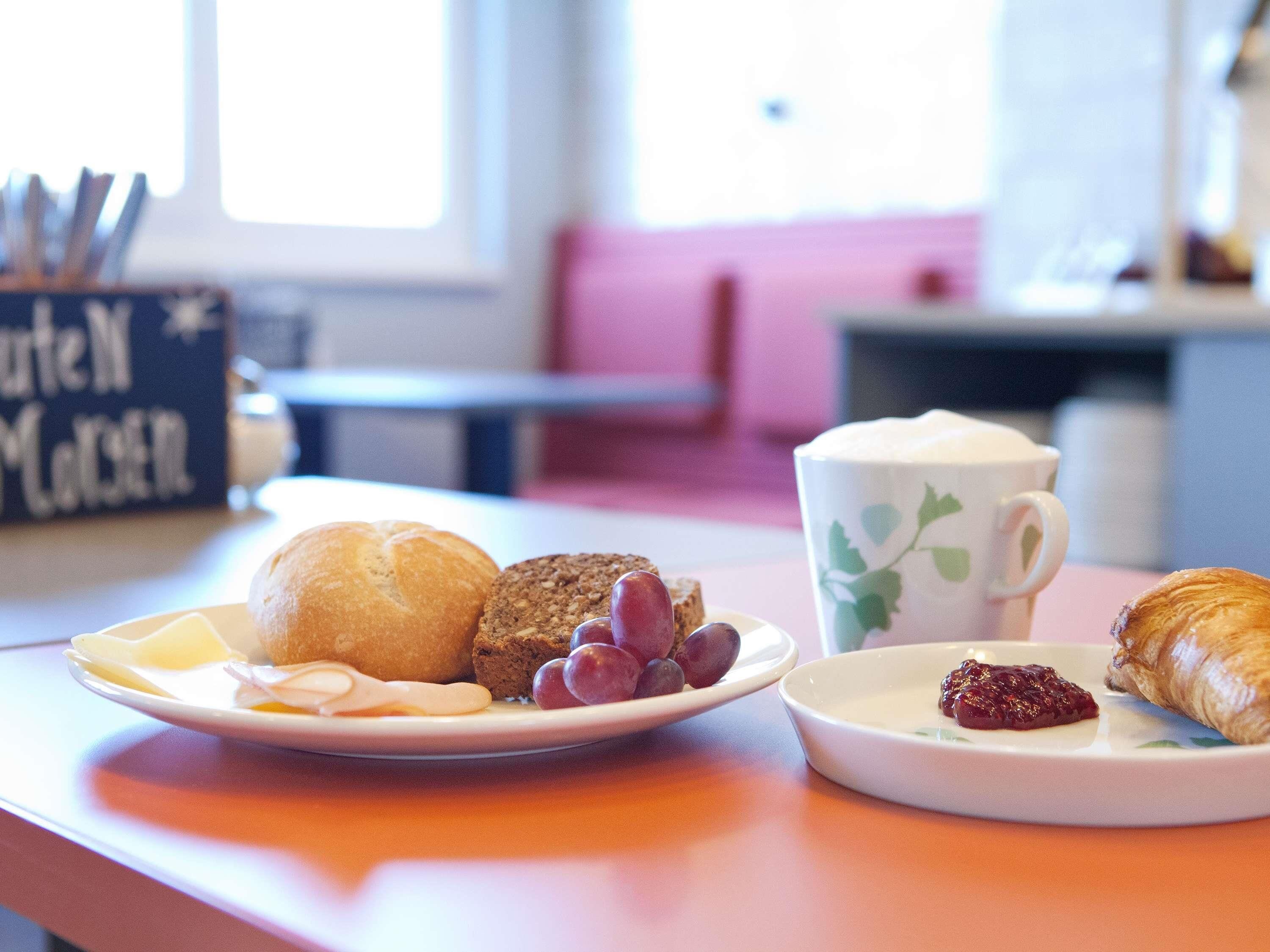A breakfast setting with a plate of food, a cup, and a croissant.