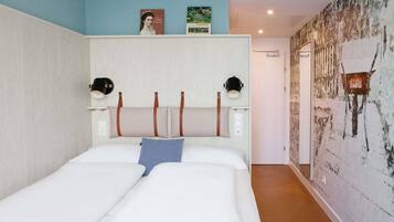 Ein Schlafzimmer mit einem Bett, zwei Wandlampen, einem Kopfteil und einer Wand mit einem Gemälde.