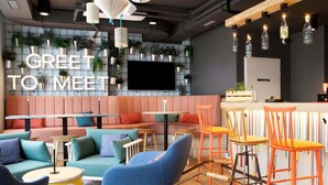 A modern lounge area with a sofa, chairs, tables, and a bar. - Greet Wien City Nord  (Vienna)