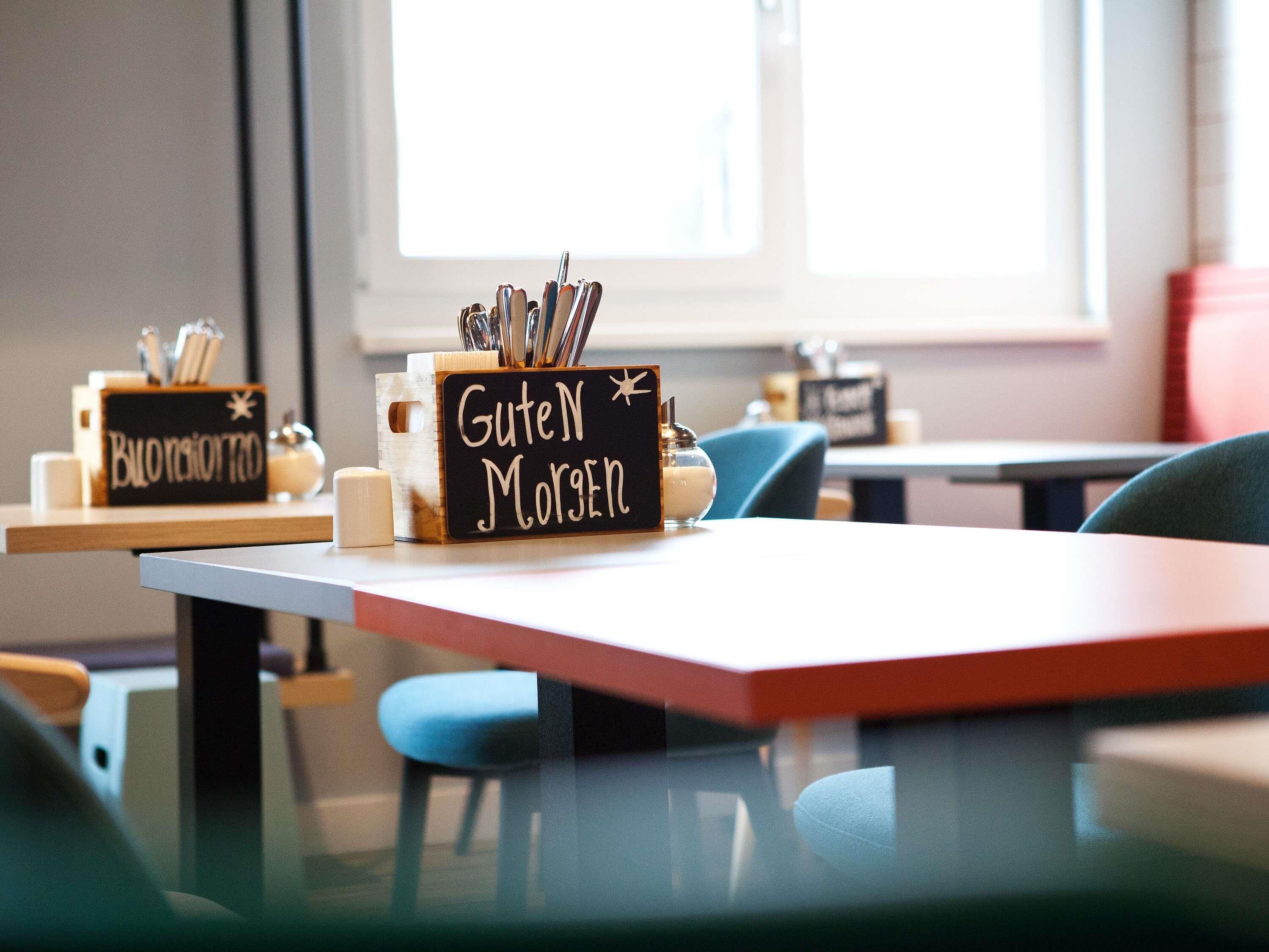 A breakfast setup with a sign reading 'Guten Morgen' and a container with utensils.