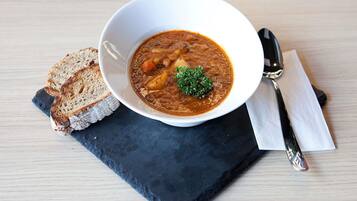 A bowl of soup with bread on a slate board.