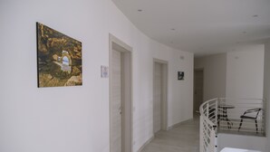 Un couloir aux murs blancs, doté d’un plancher en bois et d’un escalier muni d’une rampe.