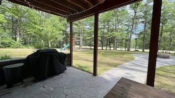 Relax on the patio surrounded by lush greenery and enjoy a meal at the wooden table.
