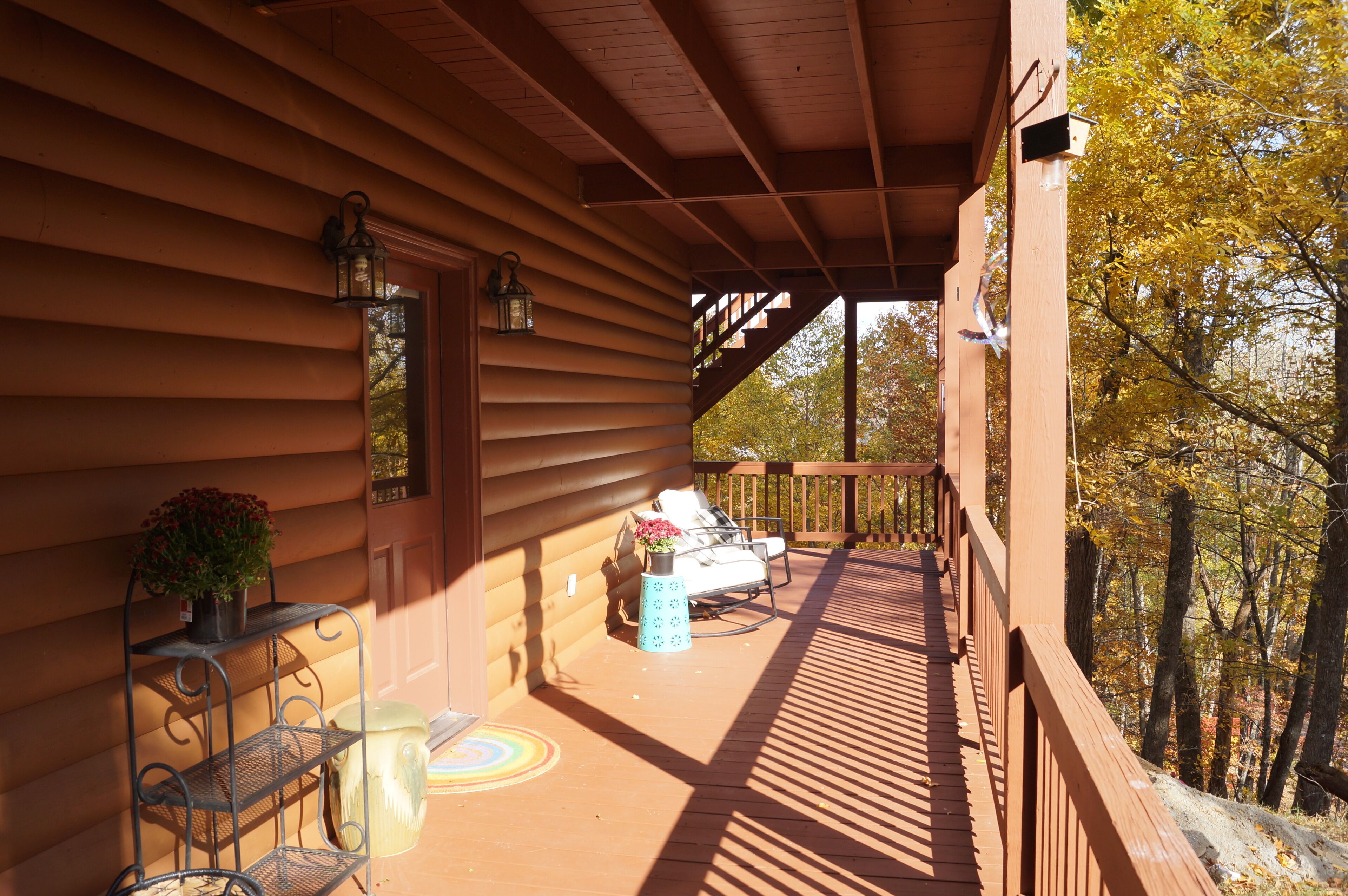 A wooden deck with a railing, a bench, a small table, and a potted plant.