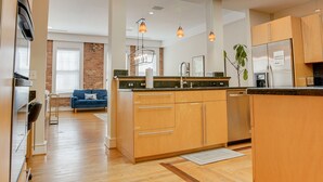 Une cuisine moderne avec des meubles en bois, un îlot central, des luminaires suspendus et une lucarne.