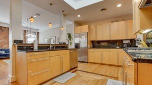 Une cuisine moderne avec des meubles en bois, des appareils électroménagers en acier inoxydable et des luminaires suspendus.