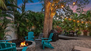 An outdoor patio with seating, a fire pit, and string lights.