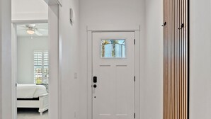 A hallway with a white door, a patterned rug, and a ceiling with wooden slats.