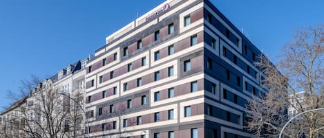 A multi-story hotel with a modern design, featuring a prominent logo at the top.