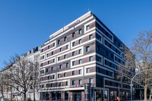 Et moderne hotel med flere etager, der har et tydeligt logo øverst.