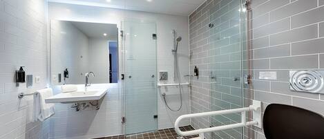 A modern bathroom with a glass shower enclosure, a white sink, and a toilet.
