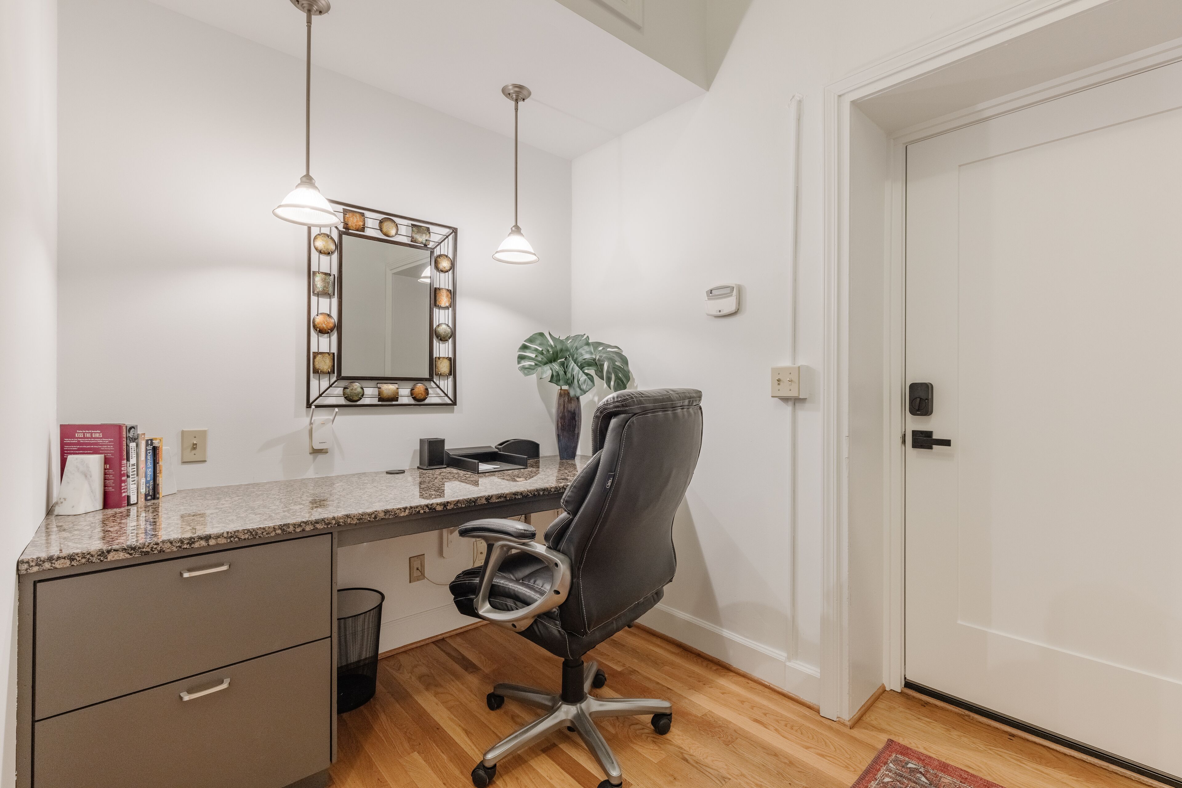 A modern office space with a desk, chair, and a large mirror with lights.