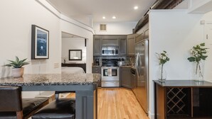 A modern kitchen with granite countertops, stainless steel appliances, and wooden flooring.