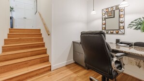 A staircase leading to a room with a desk, chair, and a mirror with lights.