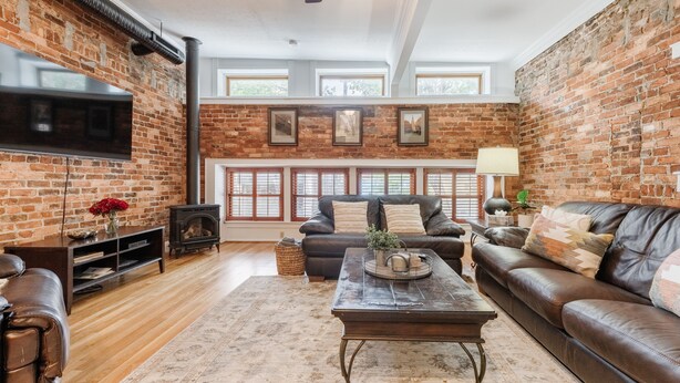 A living room with a brick wall, leather sofas, a wooden coffee table, and a fireplace.