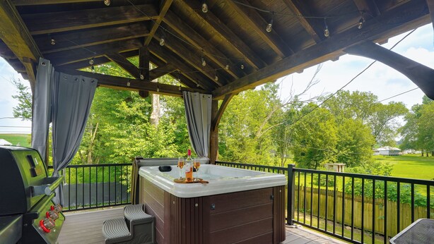 Un bain à remous sur une terrasse en bois, avec vue sur un paysage verdoyant.