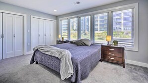 Quarto com cama grande, mesa de cabeceira, penteadeira e janela com persianas.