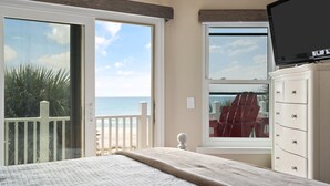 Ein Schlafzimmer mit großem Fenster und Blick auf Strand und Meer.