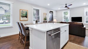 Una cucina moderna con isola centrale, mobili bianchi e lavastoviglie integrata.