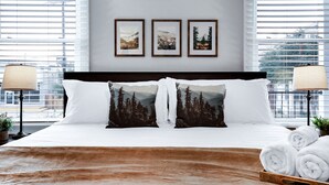 Una camera d'albergo con un letto grande, due abat-jour e tre quadri appesi al muro.