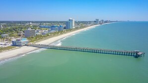 A coastal cityscape with a long pier extending into the ocean, surrounded by high-rise buildings and a beach. - Great Location minutes from Golfing & the Beach! (Myrtle Beach)