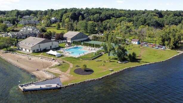An aerial view of a lakeside property with a swimming pool, a dock, and several buildings. - SARATOGA DREAM!-Lake community close to Track and Downtown (Saratoga Springs)