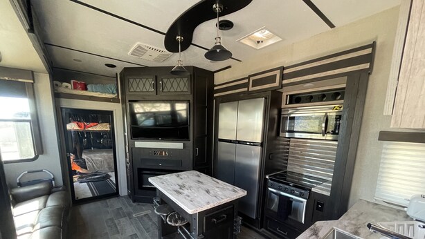 A compact kitchen with a built-in oven, microwave, and refrigerator.